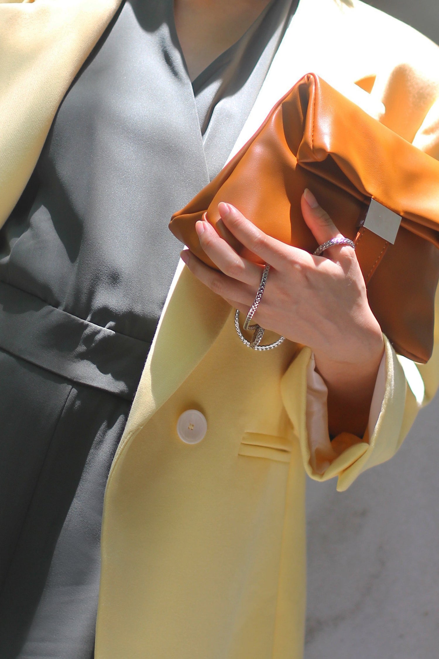 Woman wearing a yellow blazer, white top, and black pants, accessorized with a stylish handbag.