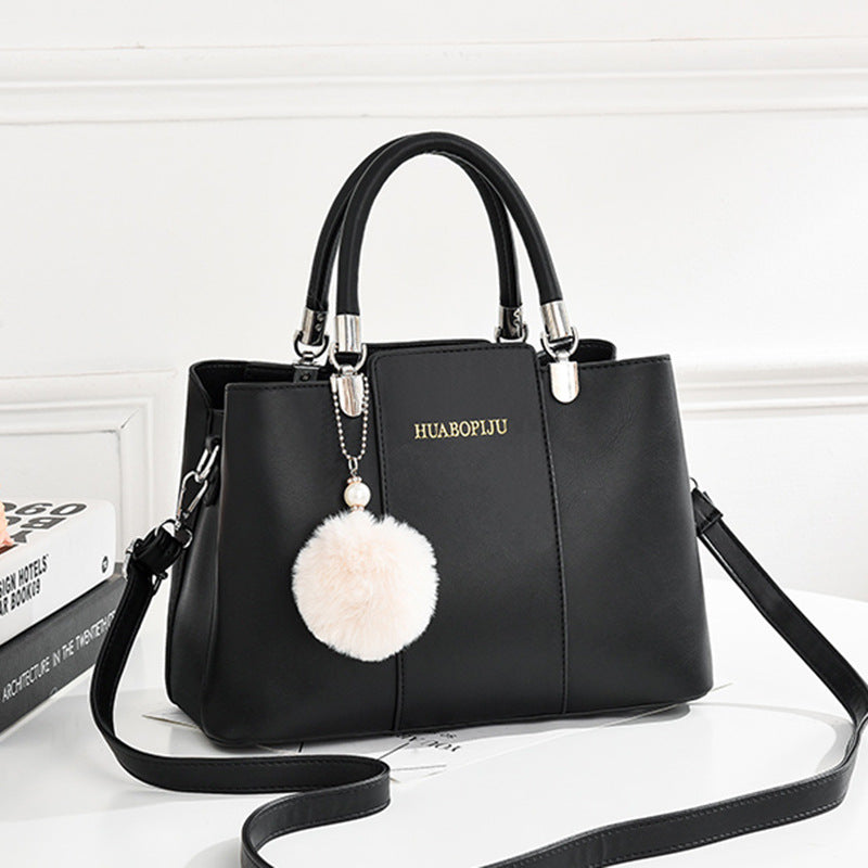 Stylish black handbag by Huabopiju adorned with a cute pom pom on the strap, complete with a zipper pocket."