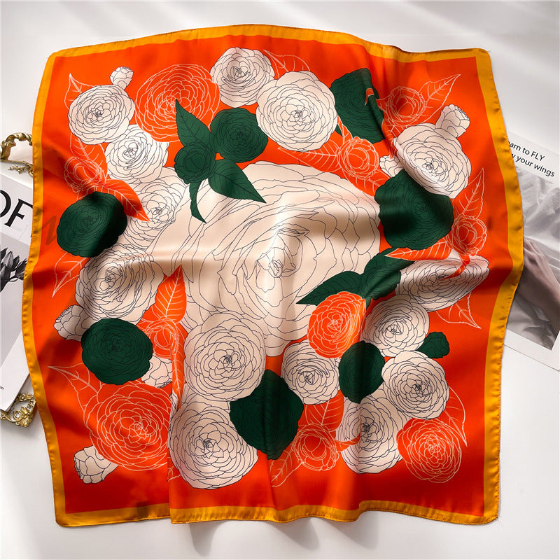 A vibrant orange and green gauze scarf with ranunculi, adding a touch of color to her outfit.