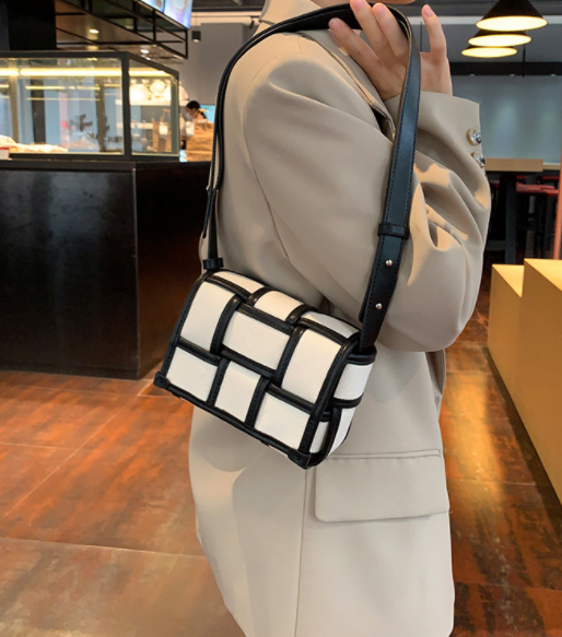 A woman wearing a black and white crossbody bag with a magnetic buckle, known as Destiny's bag.