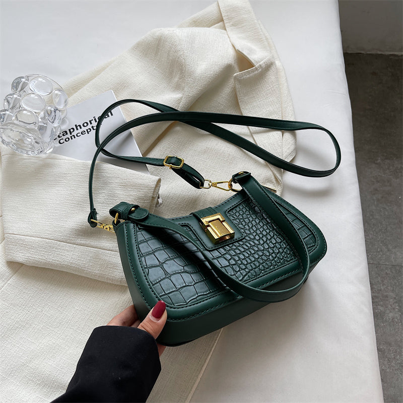 A woman holding a green crocodile skin bucket bag with gold buckle, showcasing its unique texture and vibrant color.