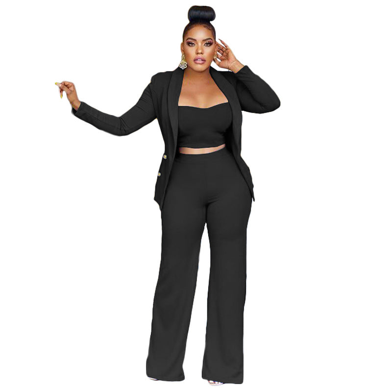 A stylish woman wearing a black crop top, pants and blazer and high heels, exuding confidence and elegance.