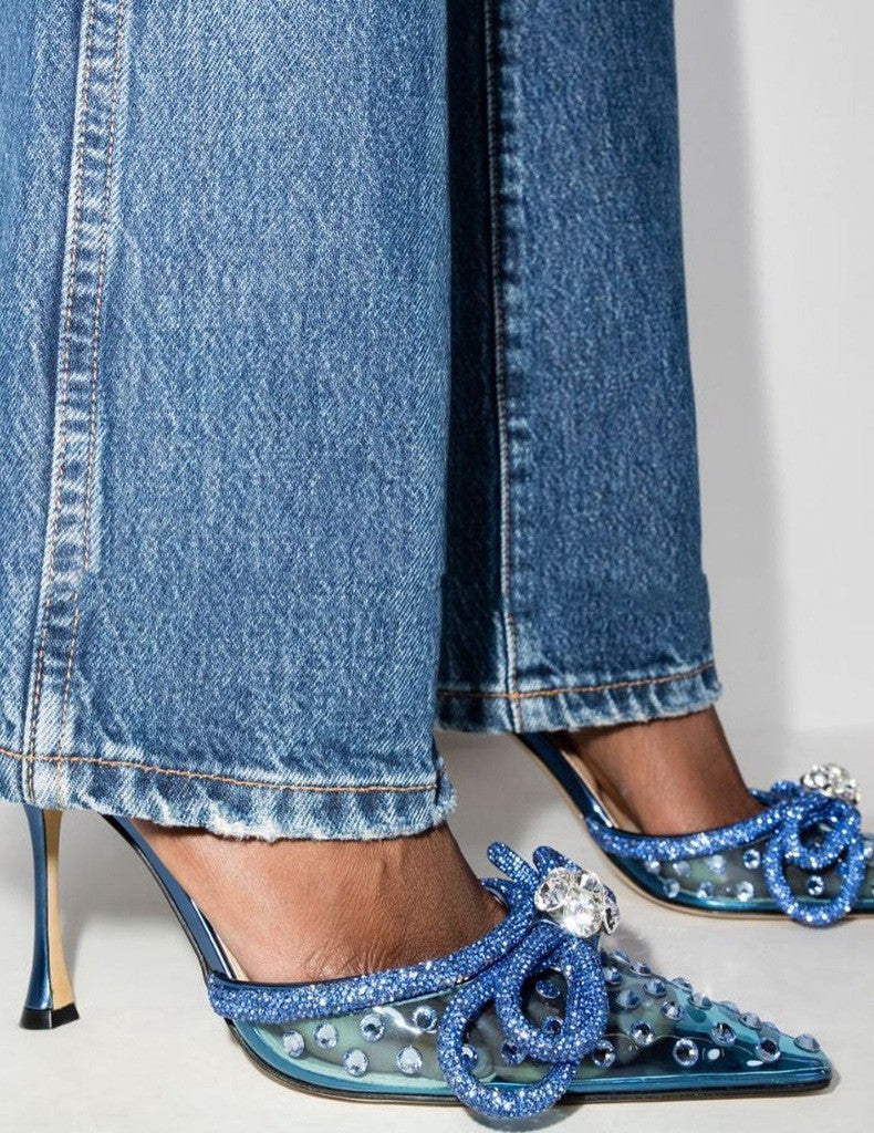 "Stylish woman in long jeans and blue heels featuring transparent rhinestone heel and bow."