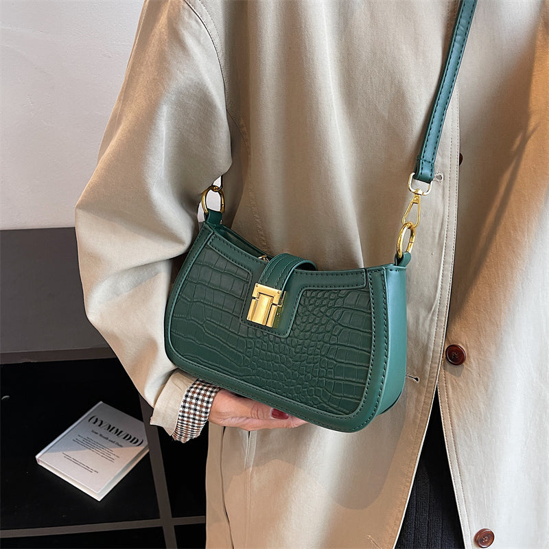 A woman holding a green crocodile skin bucket bag with gold buckle, showcasing its unique texture and vibrant color.