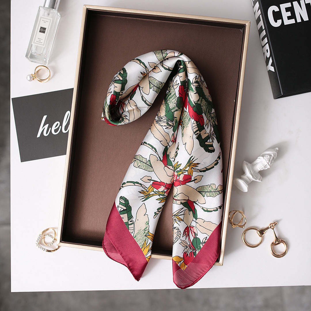 A red and white scarf neatly folded inside a box, ready to be gifted or stored.