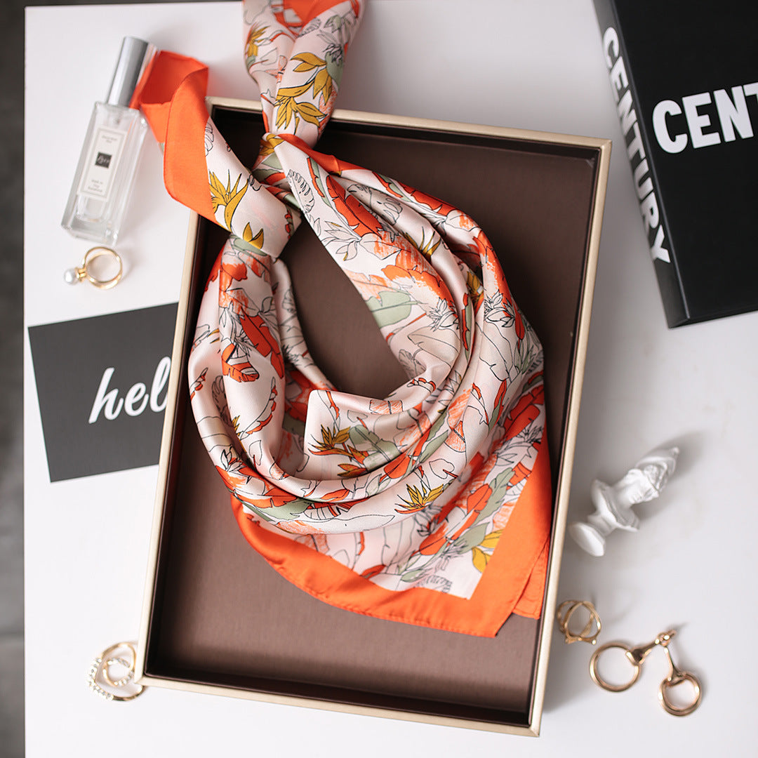 An orange and white scarf neatly folded inside a box, ready to be gifted or stored.