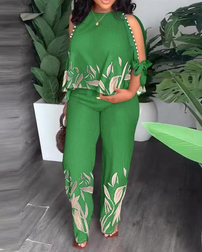 "Woman in green and gold leaf print jumpsuit, a raglan half beaded suit made of polyester fabric."