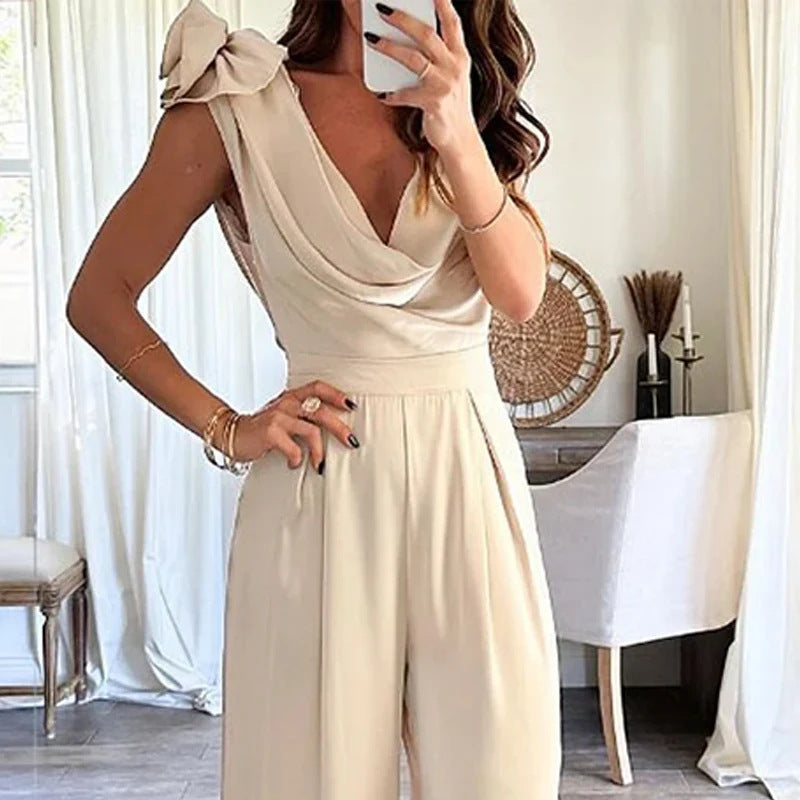 A woman in a beige low collar wide leg jumpsuit capturing a selfie.