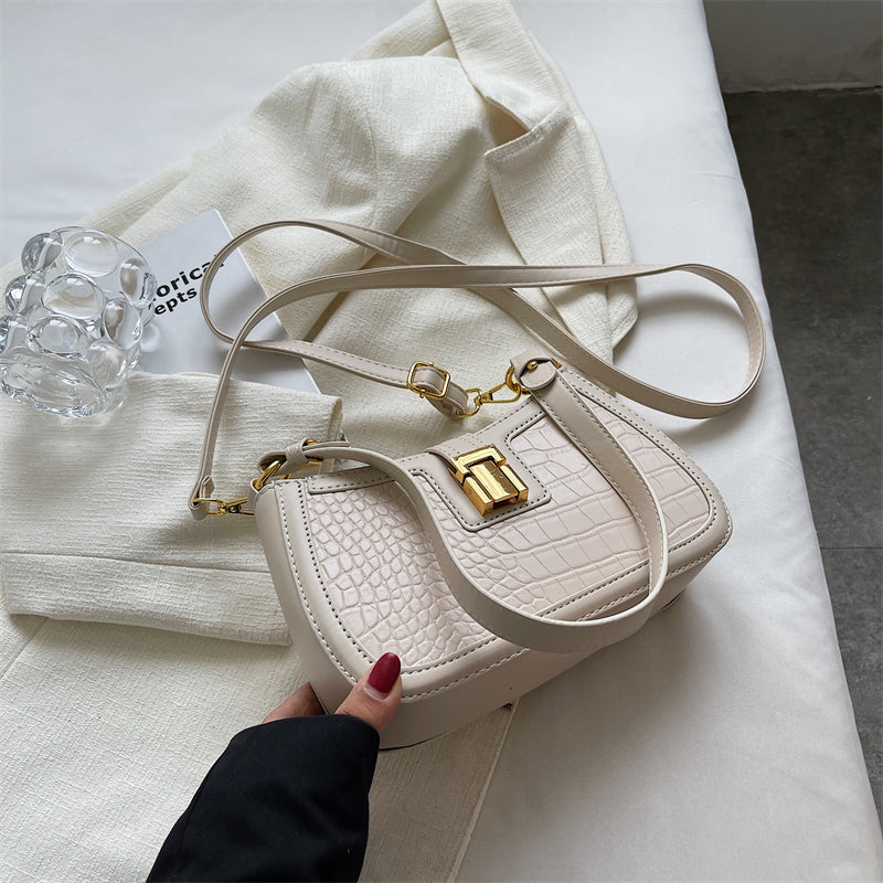 A woman holding a white crocodile skin bucket bag with gold buckle, showcasing its unique texture and vibrant color.